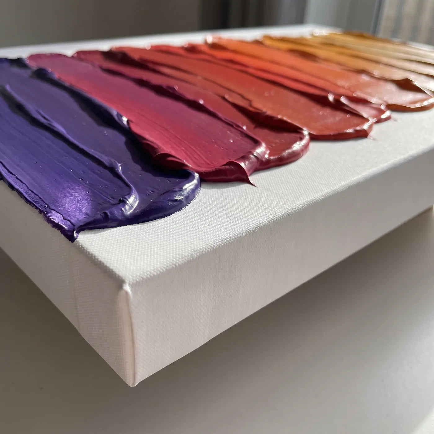 A 3D+ vászon éle oldalról — 5,8 cm mély fehér oldal és spatulával felhordott sűrű akrilfesték sávjai, mindegyik más színben, együtt lilától borostyánig tartó átmenetet adva